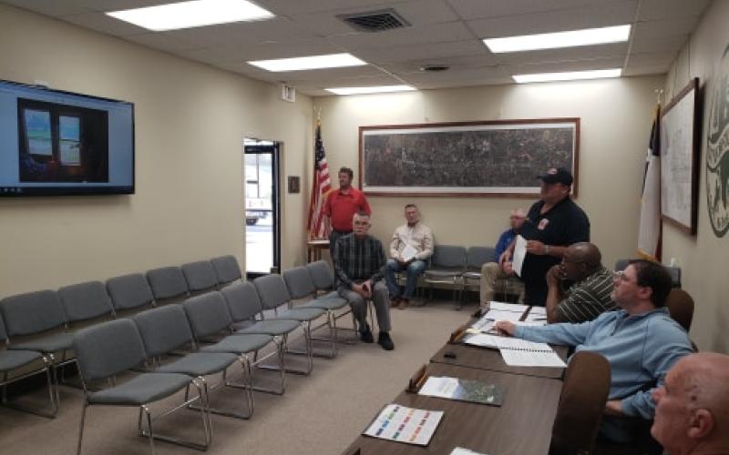 Fire Chief Calvin Chaney shows the commissioners several photos taken of houses from around town that depict substandard living arrangements. BA photo by James Norman