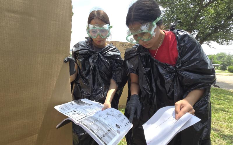Two Breckenridge High School students look over blood spatter patterns as a part of the forensic science class. The students were split into investigator teams to create spatter patterns on cardboard boxes. (BISD Journalism/Contributed photo)