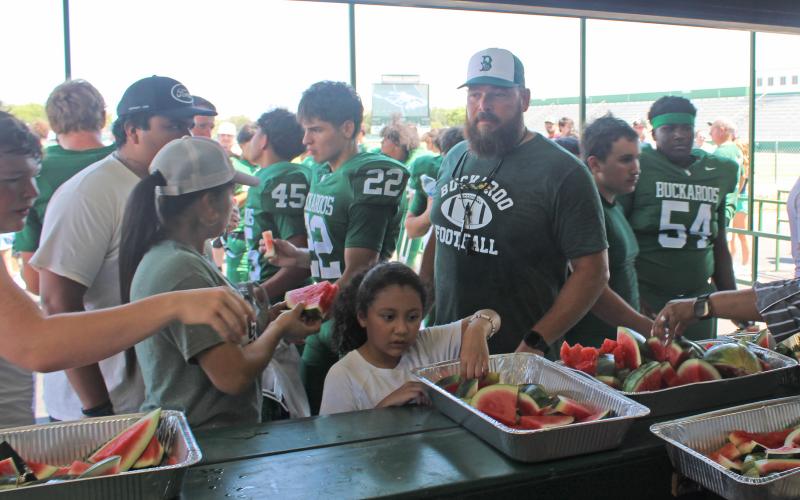 (Photo/Alex Kielar) Players, coaches and families grab watermelon following this year’s Watermelon Scrimmage at Buckaroo Stadium. The Breckenridge ISD board approved the construction of a new concession stand at the southeast end of the stadium. 