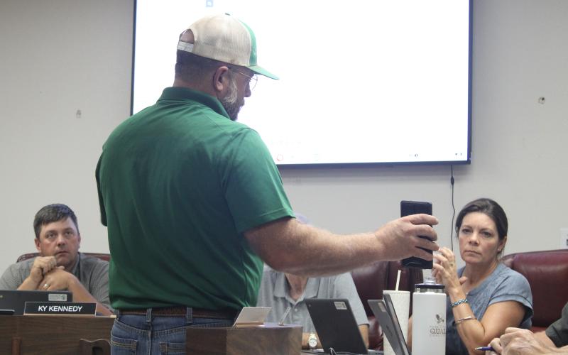 (Photo/Alex Kielar) Josh Patterson of Rockin' P Construction LLC shows the BISD school board a draft rendering on his phone of what the approved concession stand construction will look like at the southeast corner of Buckaroo Stadium. 