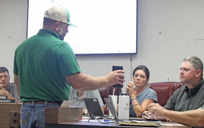 (Photo/Alex Kielar) Josh Patterson of Rockin' P Construction LLC shows the BISD school board a draft rendering on his phone of what the approved concession stand construction will look like at the southeast corner of Buckaroo Stadium. 