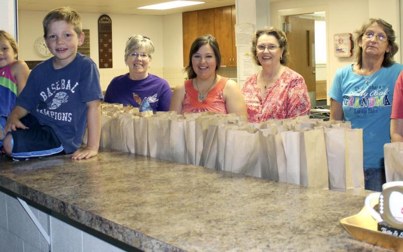 From left, area children Christian Lechner and Ashlyn Owens pose for a photo with volunteers Linda Leveridge, April Lechner, Sharon Toland, Marian Jarvis and Ginger Dittmar during the Feed My Lambs food program.
