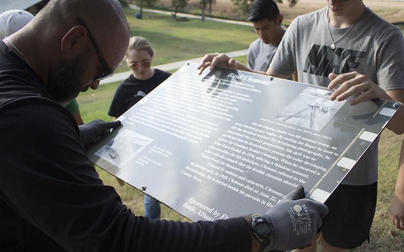 BHS Assistant Football Coach Brian Valenzuela and  senior student Braxton Post steady a historical way marker inside Breckenridge Park.