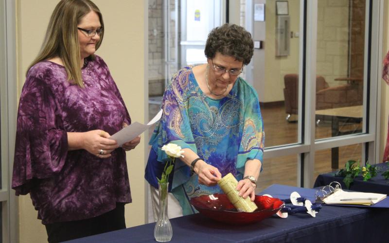 Jennifer McCormick (left) stands with Donna Hill, who lights the candle to prepare for seven new members to be inducted into Phi Theta Kappa. BA photo by James Norman