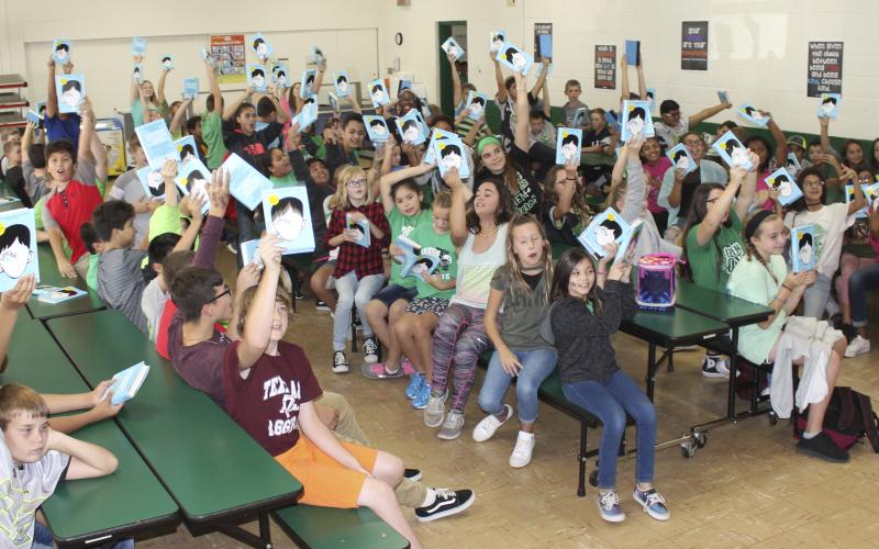 Students at South Elementary hold up their recently donated book “Wonder” as part of a multi-class project.