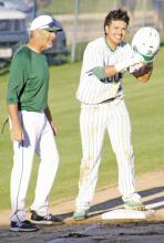 Nieko Martinez smiles at third base with coach Jeremy West after legging out a triple on a hit down the right field line in a game this season.
