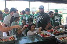 (Photo/Alex Kielar) Players, coaches and families grab watermelon following this year’s Watermelon Scrimmage at Buckaroo Stadium. The Breckenridge ISD board approved the construction of a new concession stand at the southeast end of the stadium. 