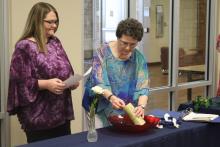 Jennifer McCormick (left) stands with Donna Hill, who lights the candle to prepare for seven new members to be inducted into Phi Theta Kappa. BA photo by James Norman
