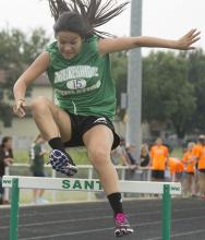 Freshman Nayeli Hernandez leaps over a hurdle after running more than 1.5 miles during the Santo Relay.